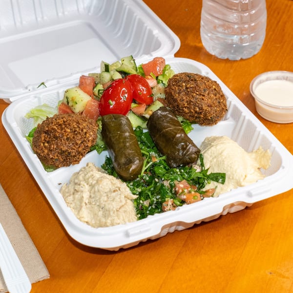 Falafel King's take-out platter with falafel, stuffed grape leaves, hummus, baba ghanoush, and salads.