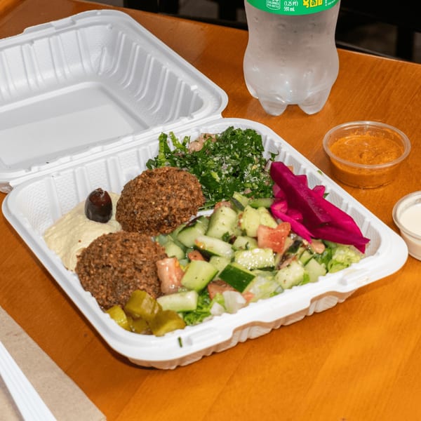 Falafel King's falafel platter with hummus, tabbouleh, cucumber salad, pickled turnips, and sauces.