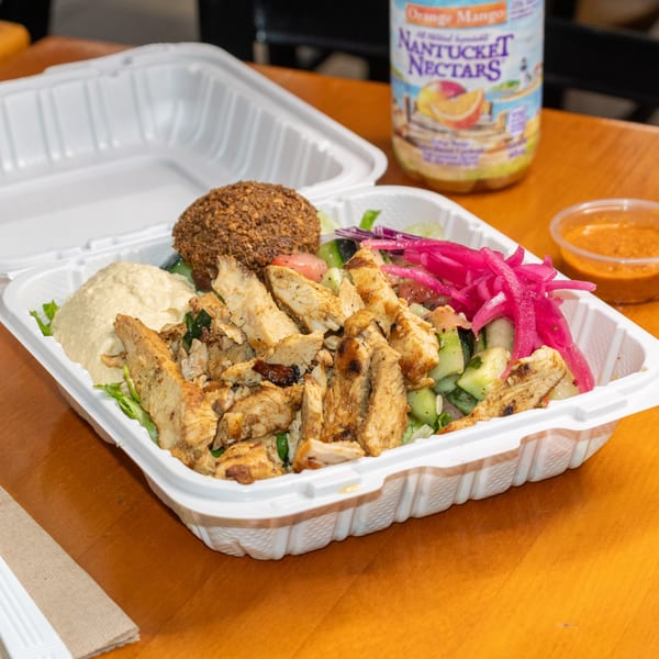Falafel King's chicken shawarma salad with hummus, falafel, pickled onions, and a drink.