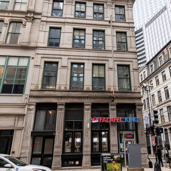 The Falafel King restaurant storefront with a red and blue neon sign on a multi-story building.