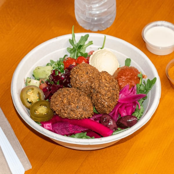 A Falafel King bowl with falafel, hummus, pickled vegetables, jalapeños, and salad greens.