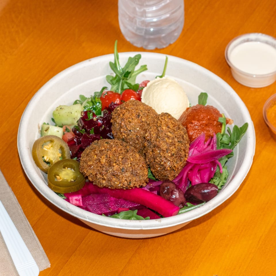 Falafel King bowl with falafel, hummus, pickled vegetables, jalapenos, olives, and salad.